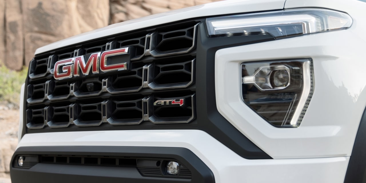 Close-Up Of the Front Grille Of a White 2027 GMC Canyon AT4X Truck With the GMC Logo and AT4X Badge