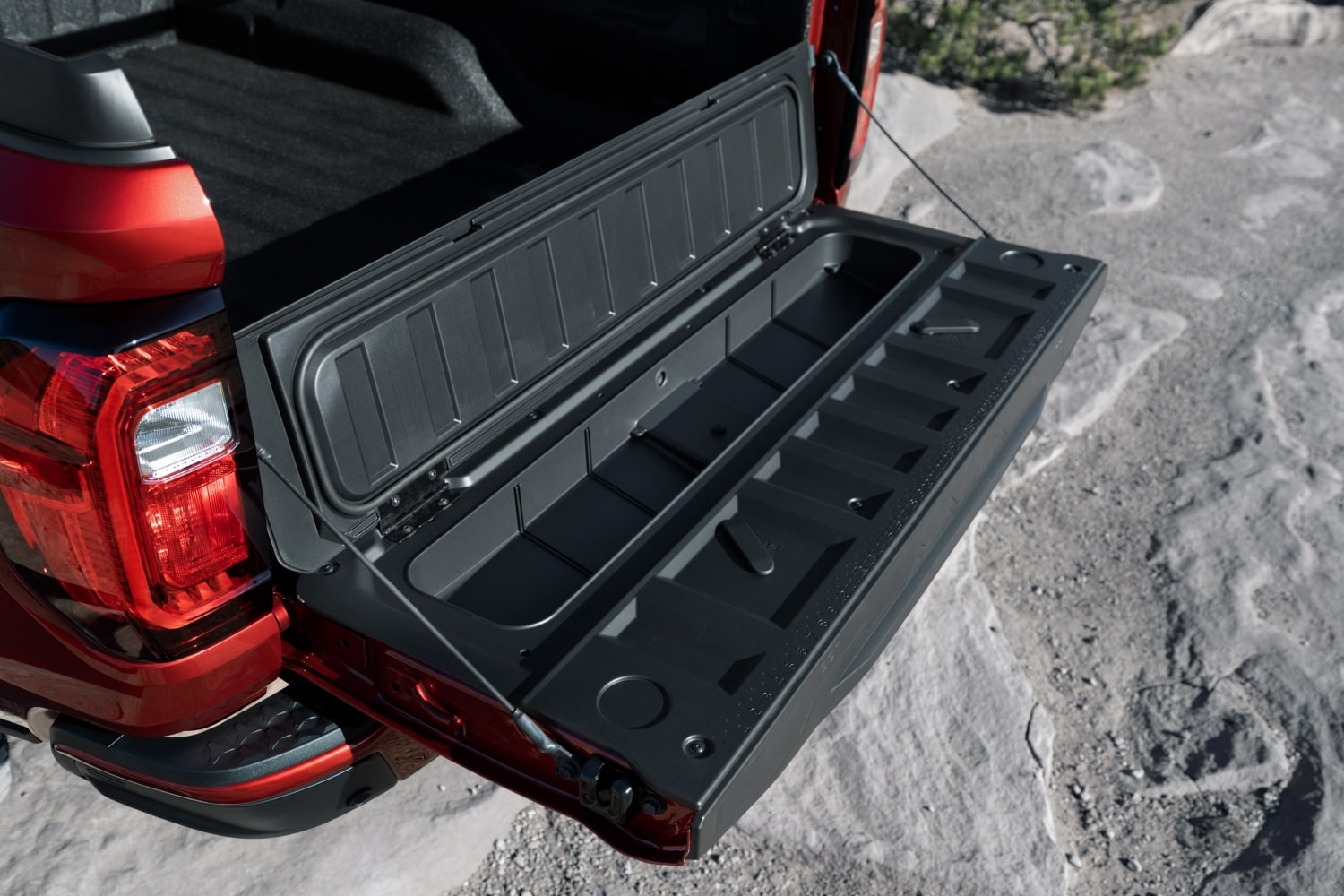 The Open Tailgate Of a Red 2027 GMC Canyon Truck Showing an Integrated Storage Compartment