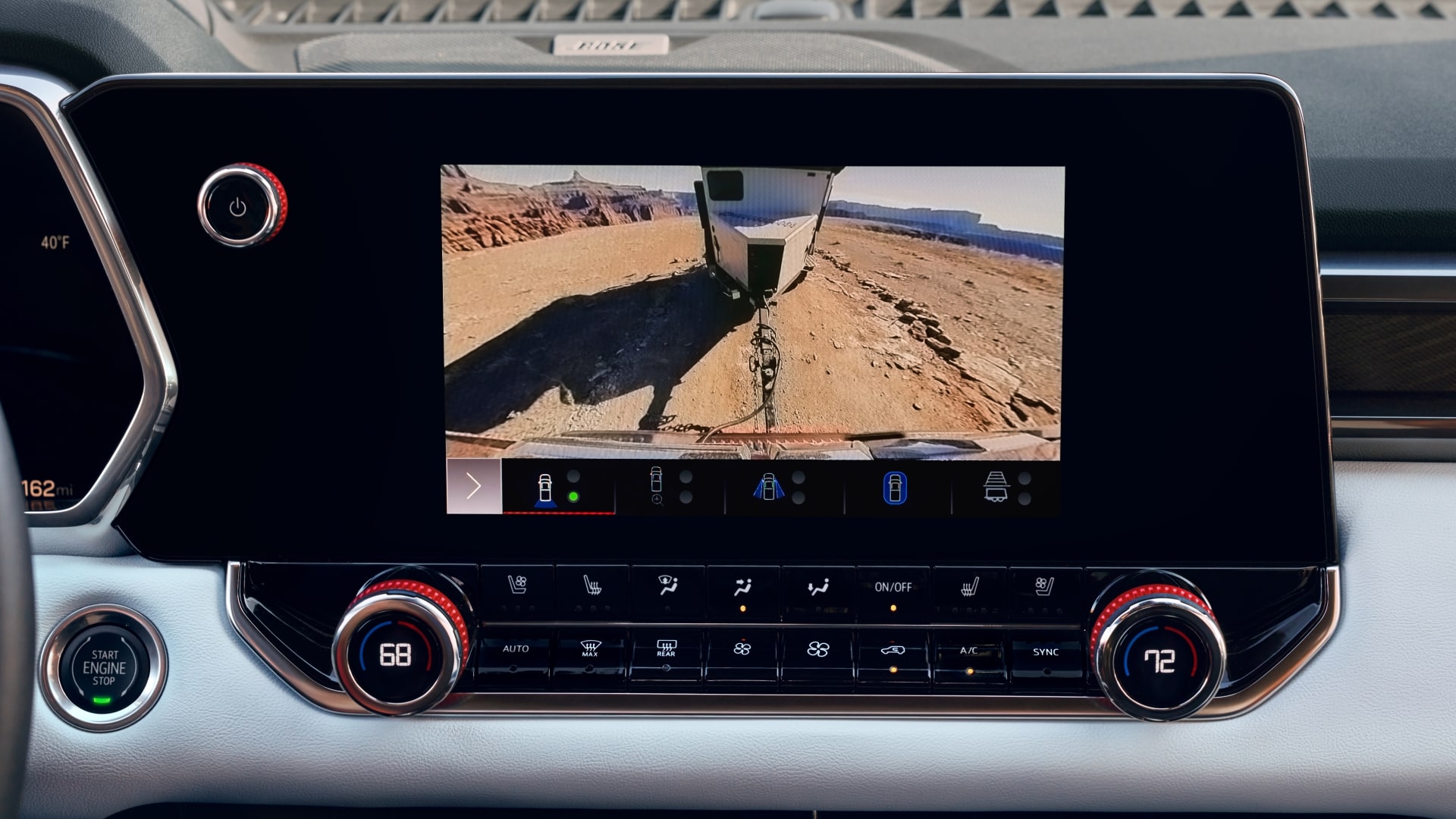 The Interior Dashboard of a 2027 GMC Canyon with an Infotainment Screen Showing a Close-Up Camera View of the Ground with a Vehicle Panel