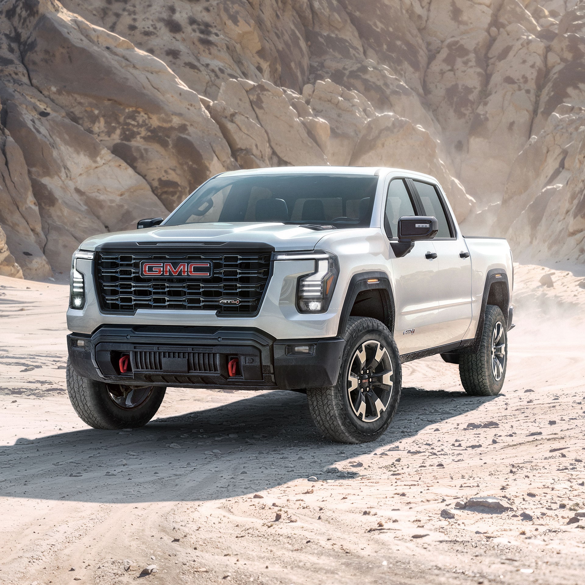A White GMC Sierra 1500 AT4X Truck Parked on a Dirt Trail With Rugged Terrain in the Background