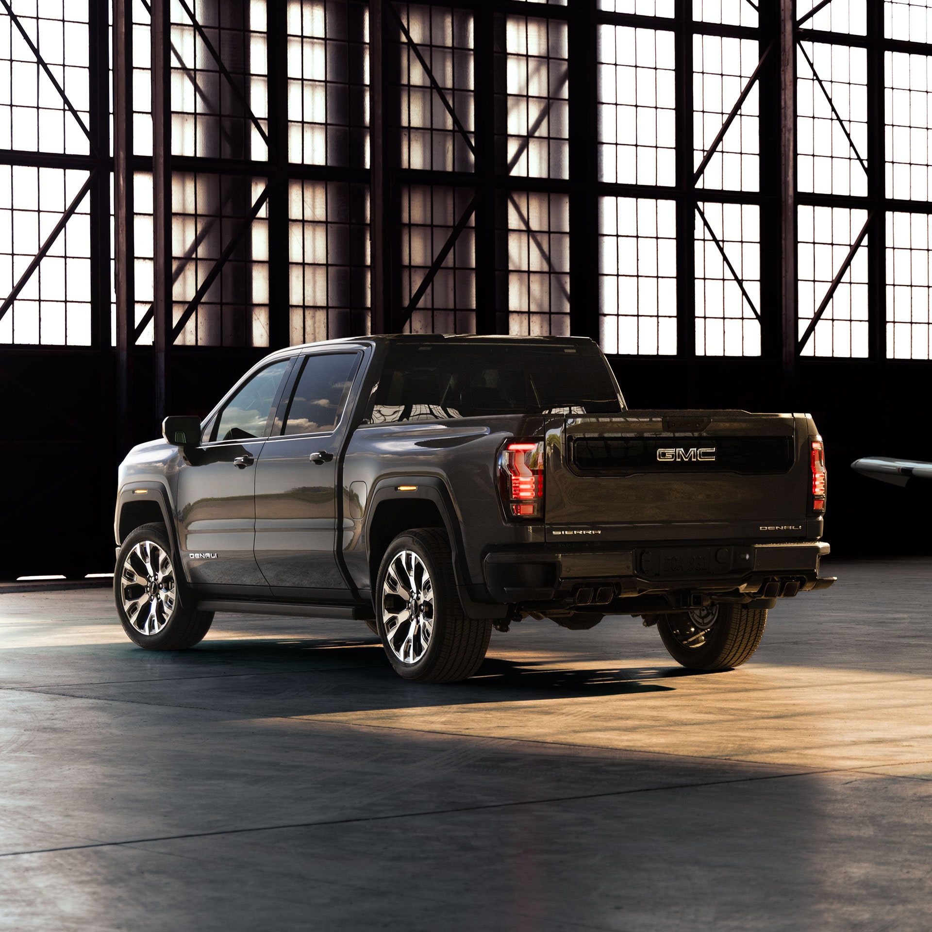 A Rear 3/4 View of a Dark GMC Sierra 1500 Denali Parked inside a Hangar with an Airplane Wing