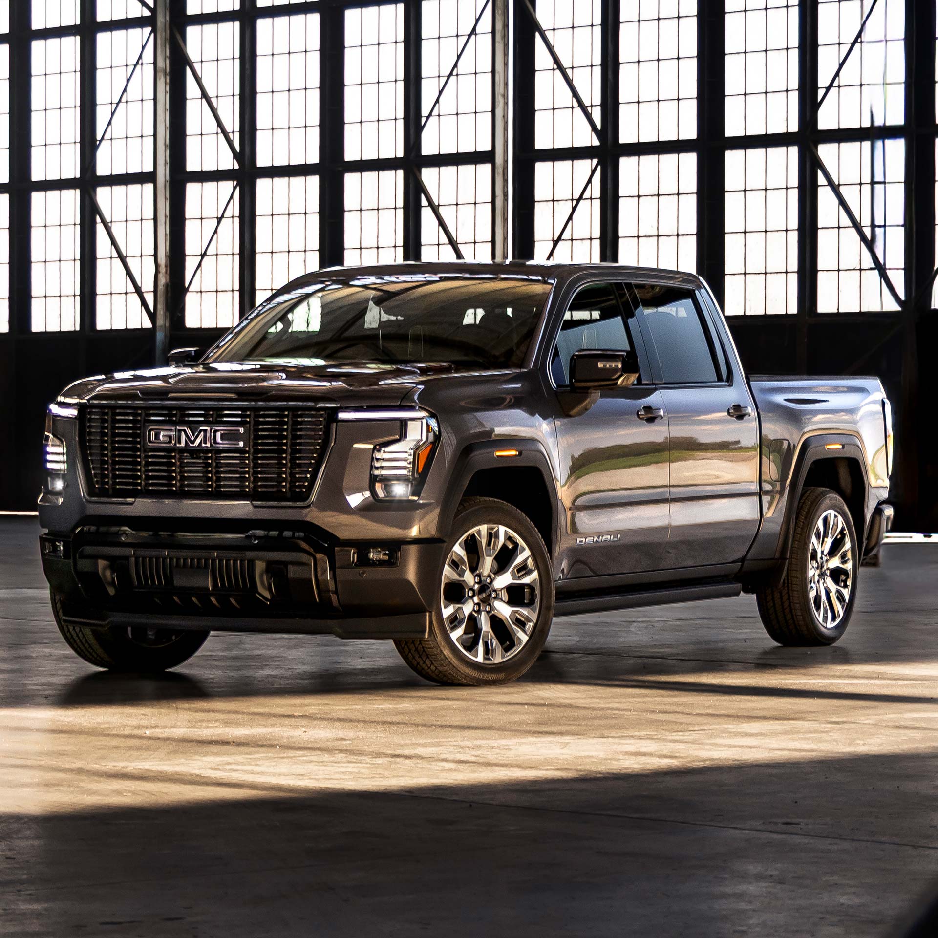 A Dark Gray GMC Sierra 1500 Denali Truck Parked in a Large Industrial Building Bathed in Sunlight