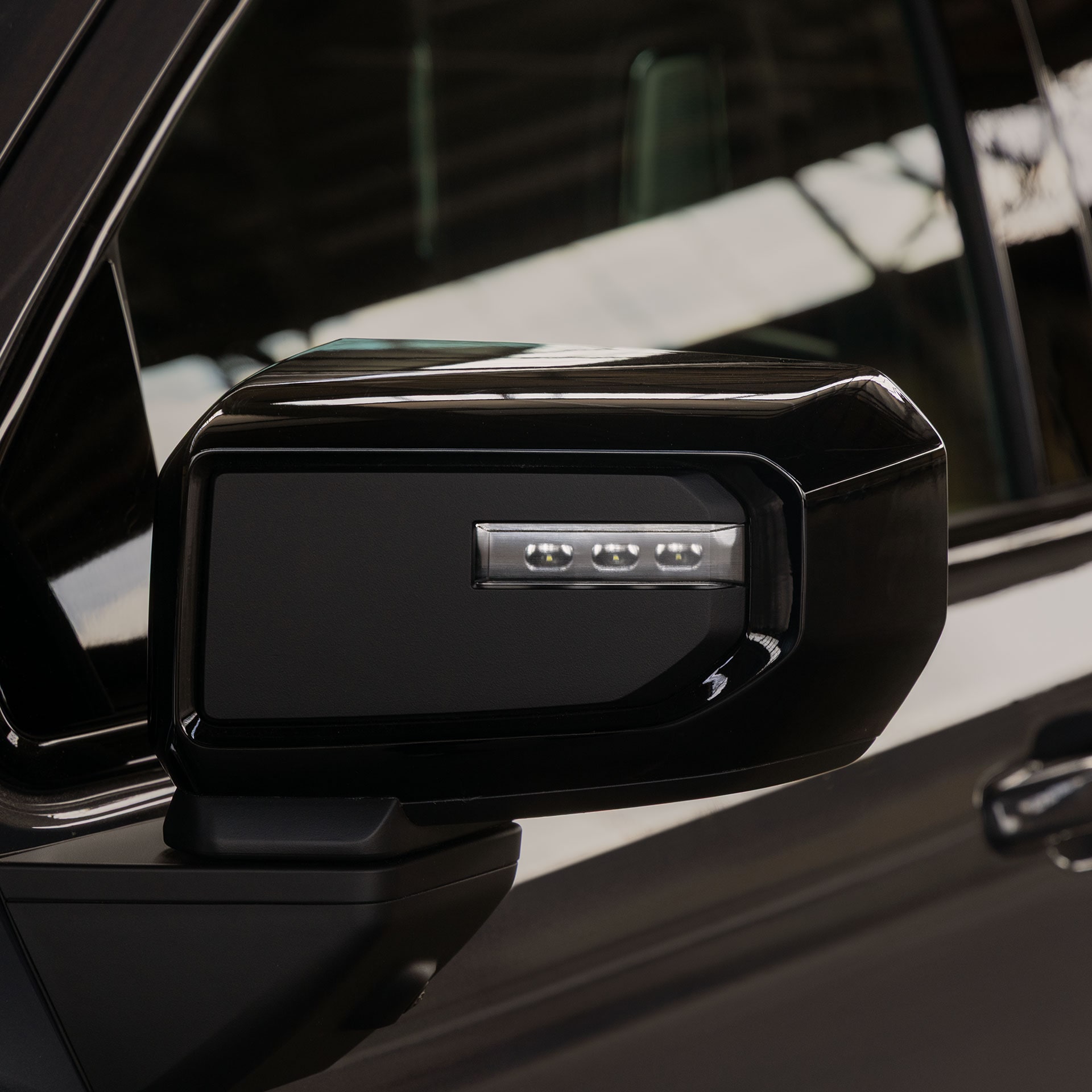 A Close Up of the Black Side Mirror With Integrated Turn Signals on the GMC Sierra 1500 Truck