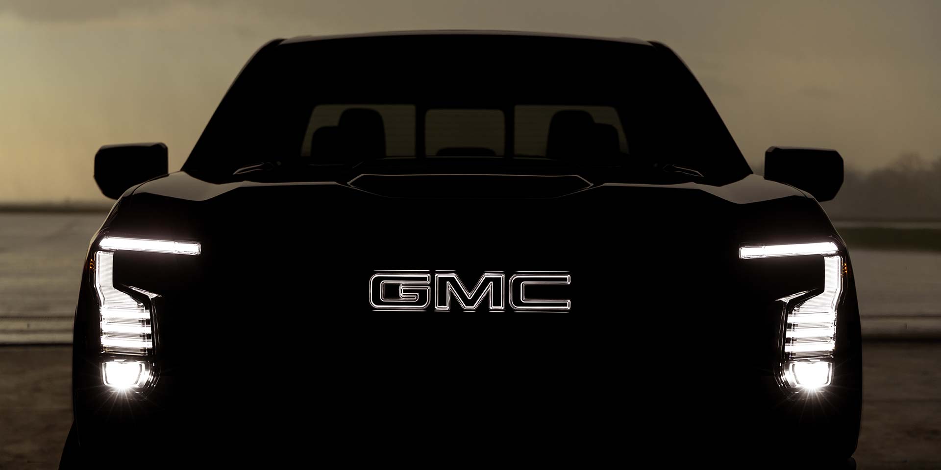 The Illuminated Front Grille and LED Headlights of a Dark GMC Sierra 1500 Truck