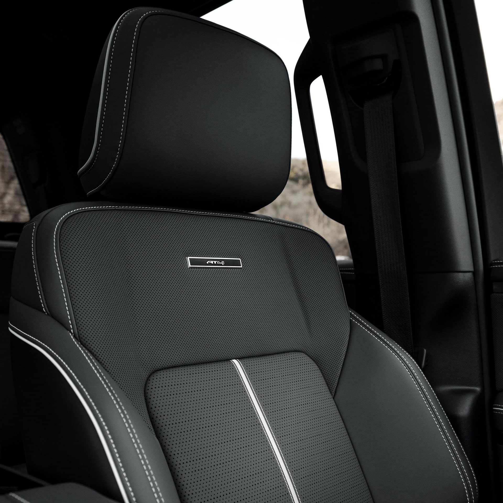 A Close-up View of the Perforated Black Leather Seat with White Stitching and AT4X Badge