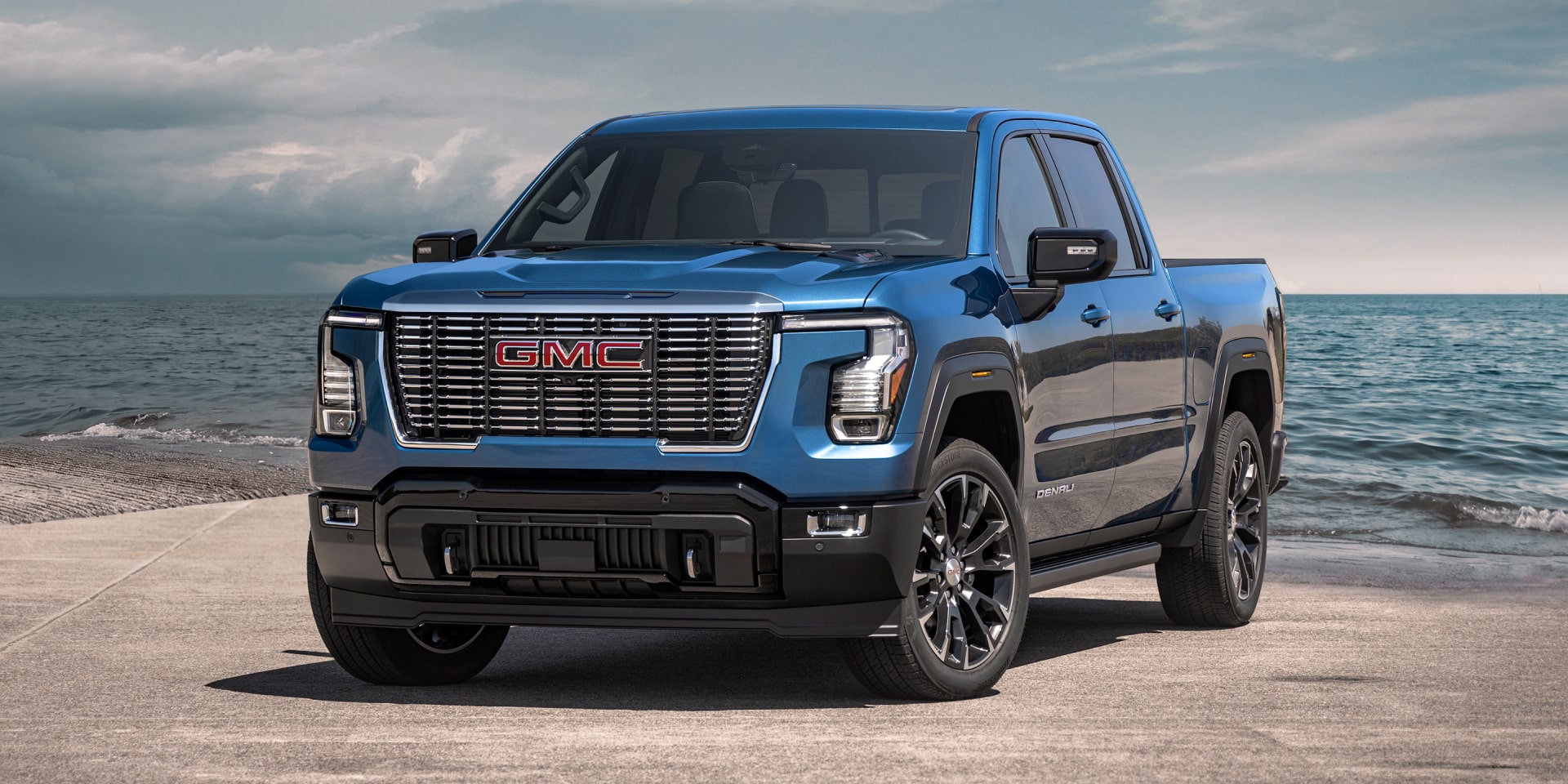 Blue 2027 GMC Sierra 1500 Denali parked by the ocean