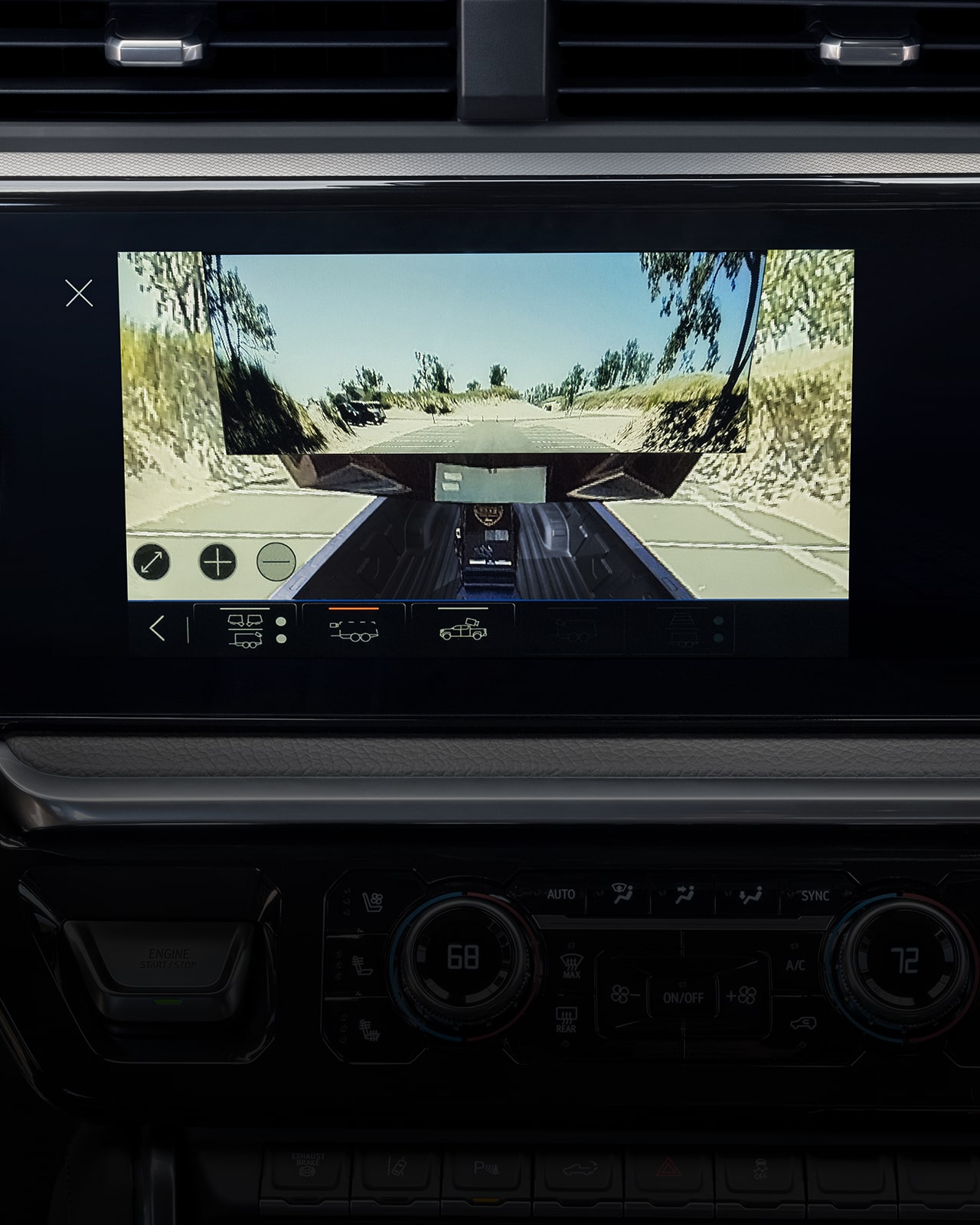 The Interior Dashboard of a 2027 GMC Sierra HD Showing a Large Infotainment Screen Displaying a Trailer Camera View On a Winding Road