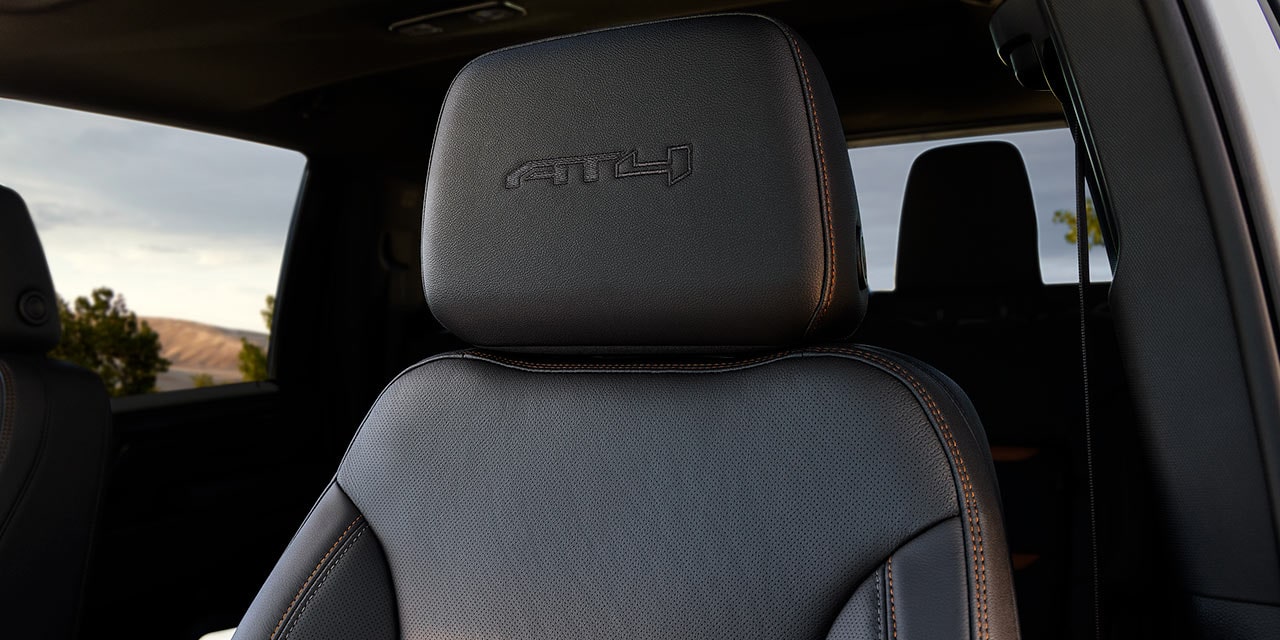 A Close-Up of a Black Leather GMC Sierra HD AT4X Seat Headrest with an Embossed AT4X Logo and Orange Stitching