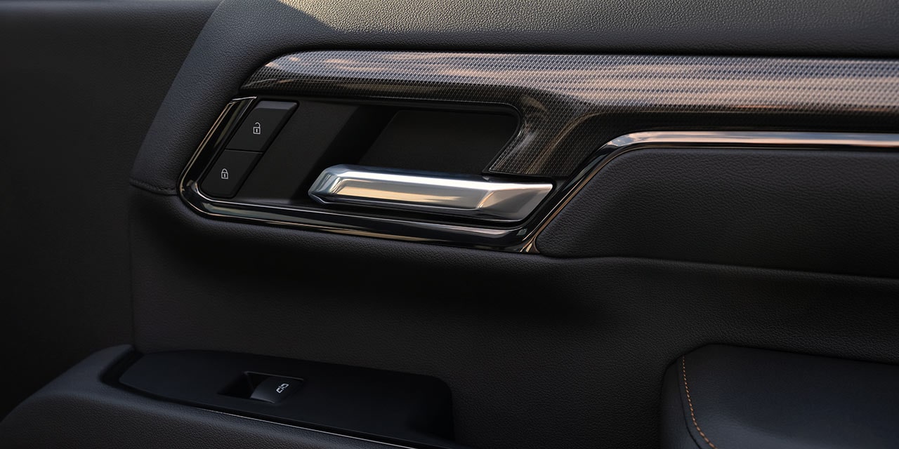 A Close-Up of the Interior Door Panel of a GMC Sierra HD AT4X Truck with a Chrome Handle and Wood-Grain Trim