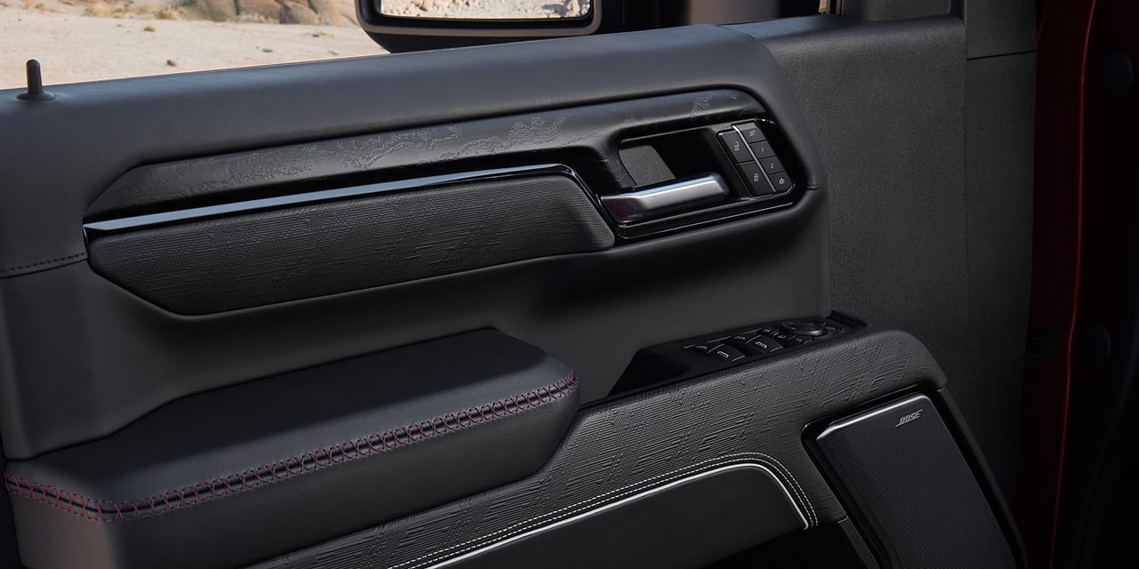 Close-Up of the Black Interior Door Panel of a GMC Sierra HD with Red Stitching
