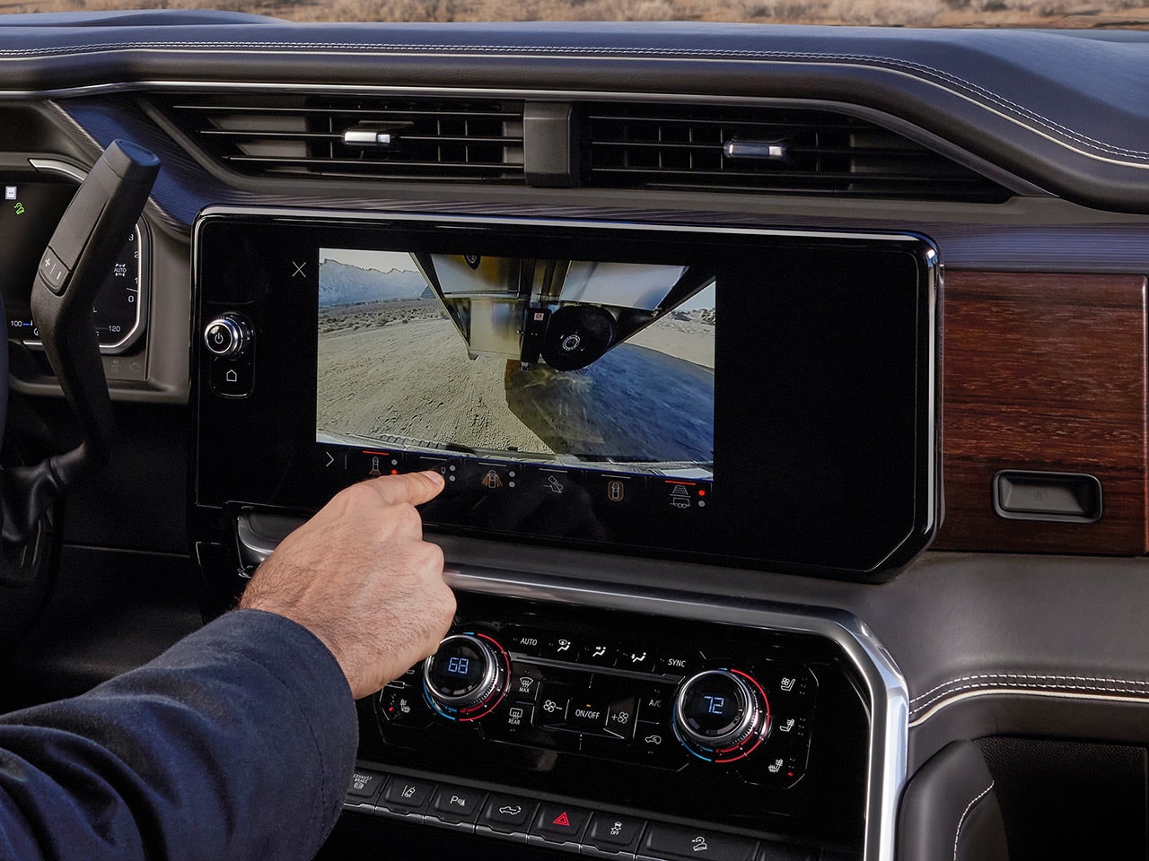 An Interior View of the 2027 GMC Sierra HD Infotainment Screen Showing a Trailer Camera View with a Hand Interacting with the Display