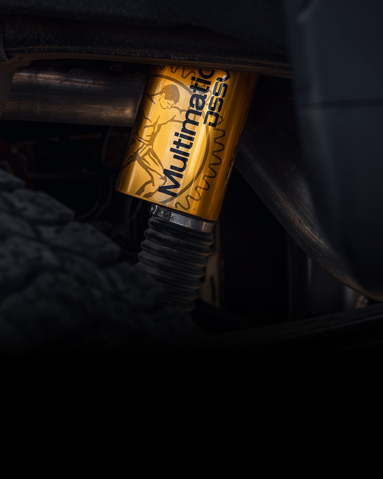 A Close-up View of a Yellow Multimatic DSSV Shock Absorber next to a Tire
