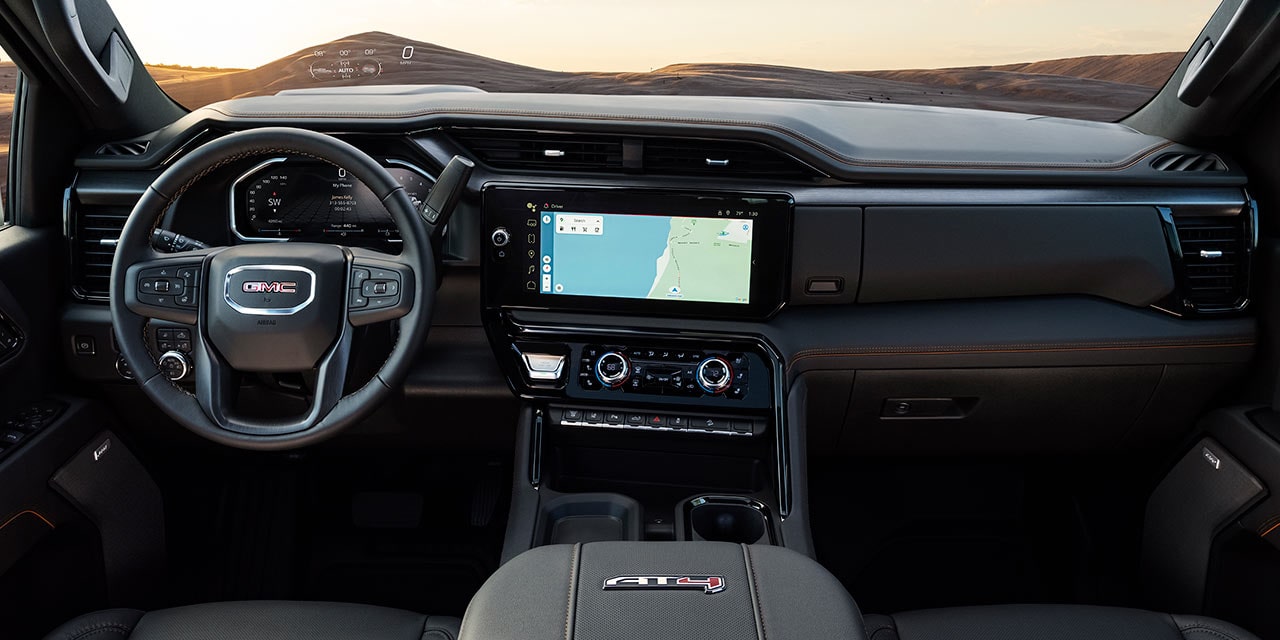 The Interior Dashboard of a GMC Sierra HD AT4X Truck with the Steering Wheel and Infotainment Screen Displaying a Map