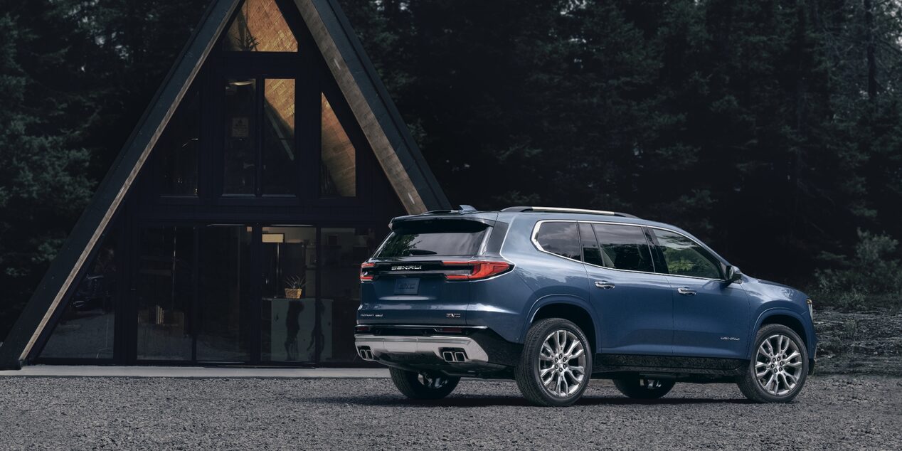 Blue 2024 GMC Acadia parked in front of a-frame house
