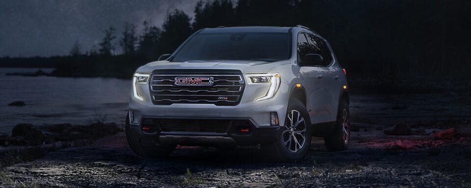 The 2024 GMC Acadia AT4 Parked Off-Road at Night with the Lights On