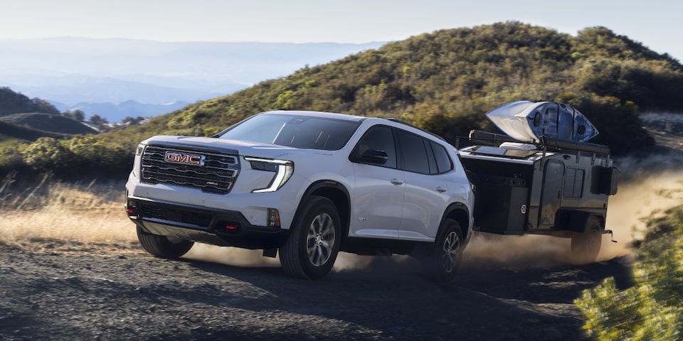Wide Front Three-Quarters View of a 2024 GMC Acadia AT4 SUV Hauling a Small Trailer