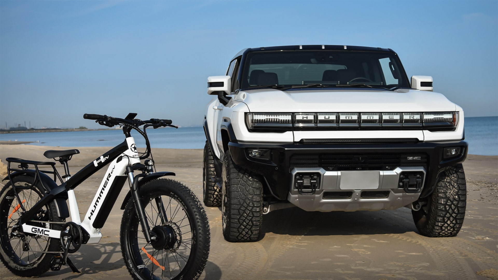 Front View of the GMC HUMMER EV Pickup Parked on the Beach with a AWD Electric Bike Powered by Recon