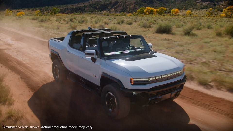 GMC Hummer EV truck driving on dirt road