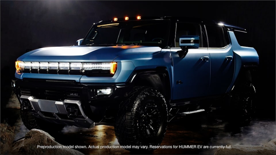 A Parked GMC HUMMER EV in a Showroom with Two Gentlemen Inside