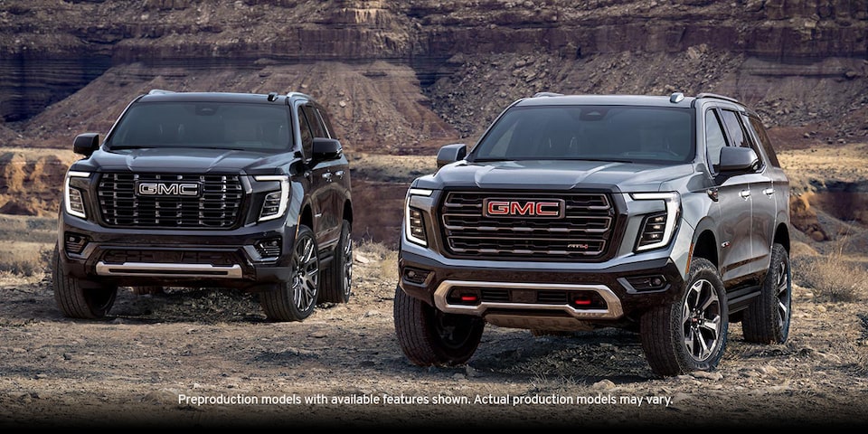Two GMC Yukon Full-Size SUV's Parked Next to Each Other with Mountains in the Background