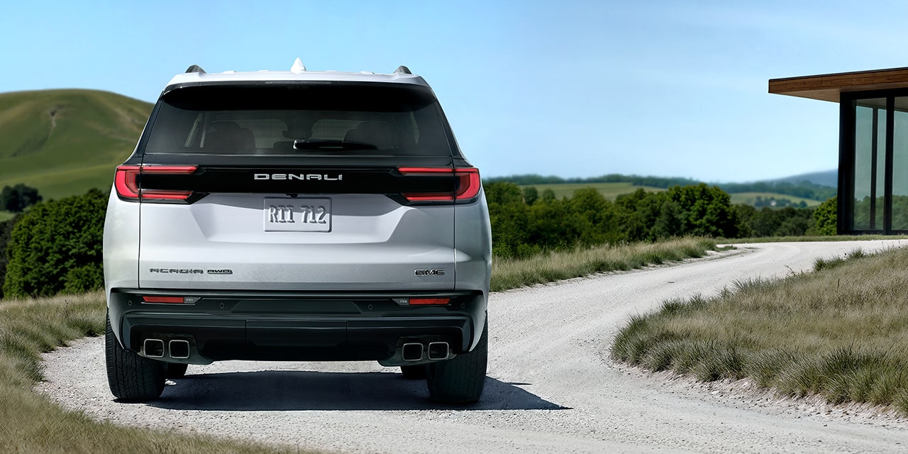 Rear View of the 2026 GMC Acadia Denali Ultimate Luxury Mid-Size SUV Driving Towards a Modern House