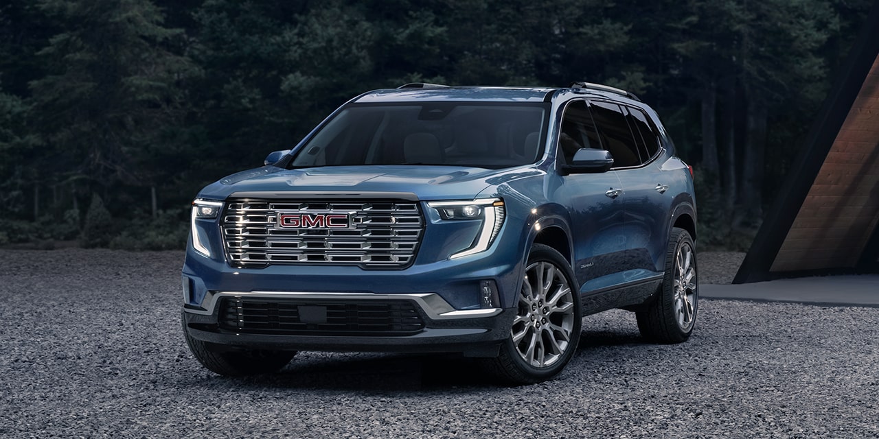 The GMC Acadia Denali Luxury Mid-Size SUV Parked on a Beach with a Forest View in the Background