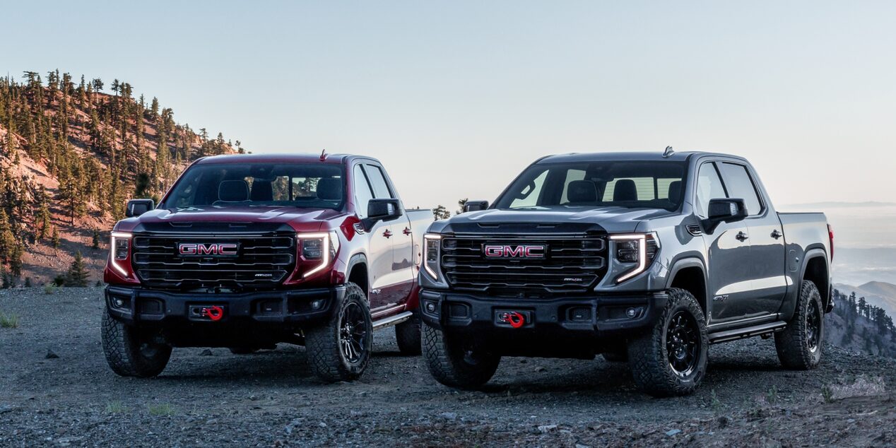Two 2023 GMC Sierra 1500 AT4X models with hills in the background