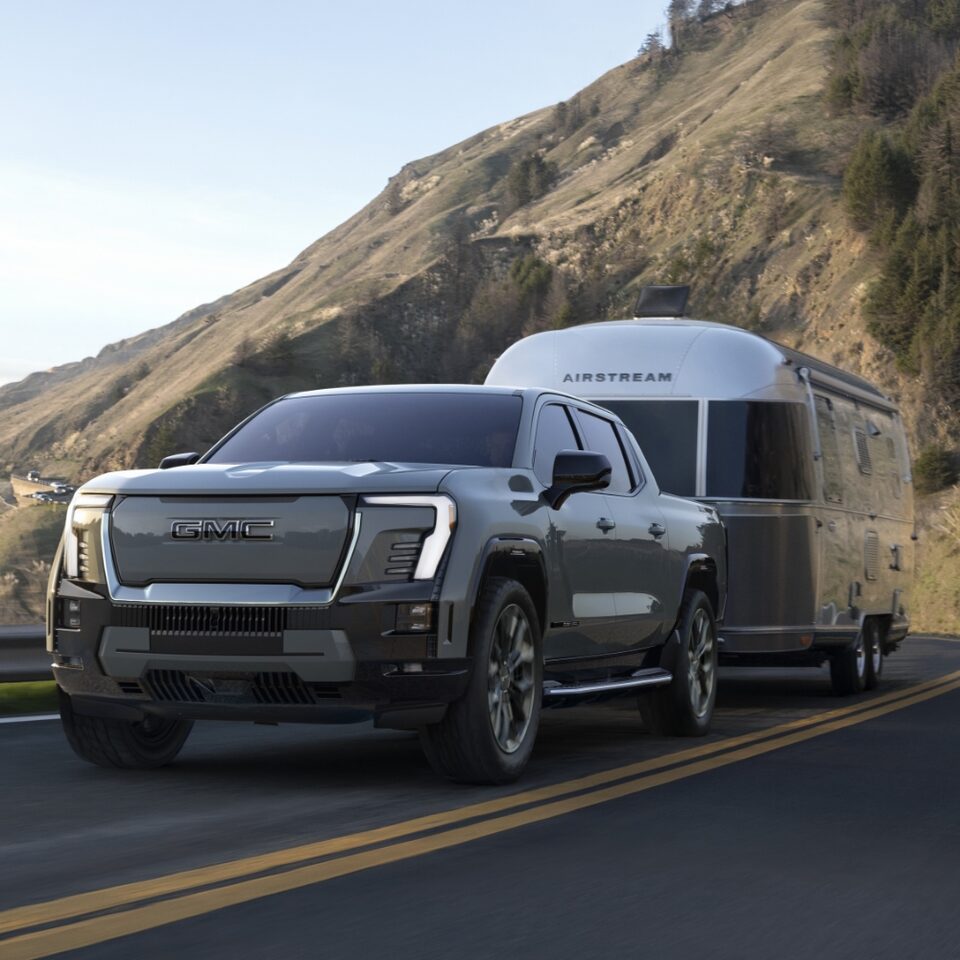 The GMC Sierra EV Denali Driving On-Road Towing a Trailer