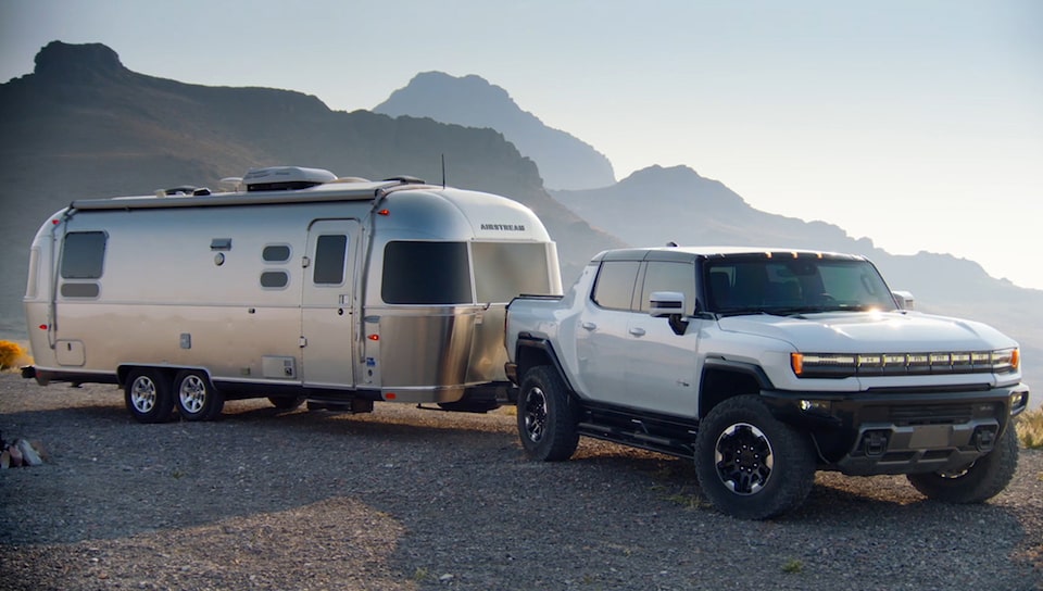 The Hummer EV Pickup Towing a Boat on an Open Roadway