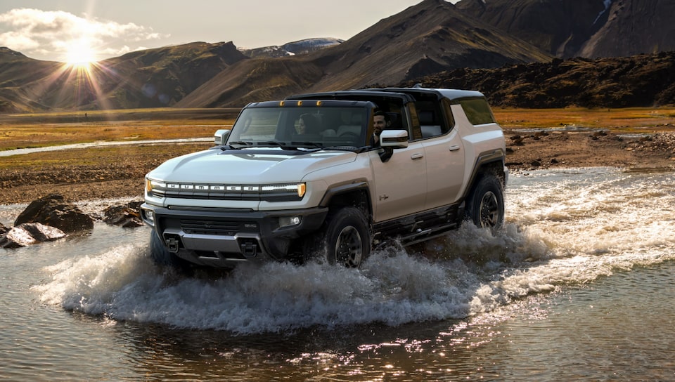 The GMC HUMMER EV SUV Driving Off-Road through Mud and Water