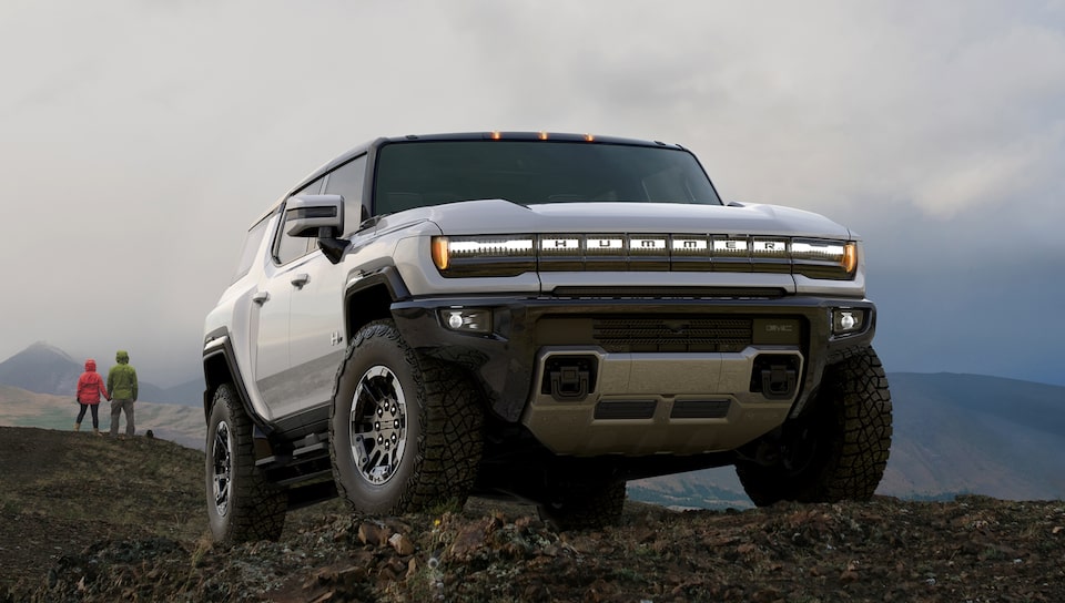 The Hummer EV Pick Up Parked on a Mountain as Two People Admire the View in the Distance 