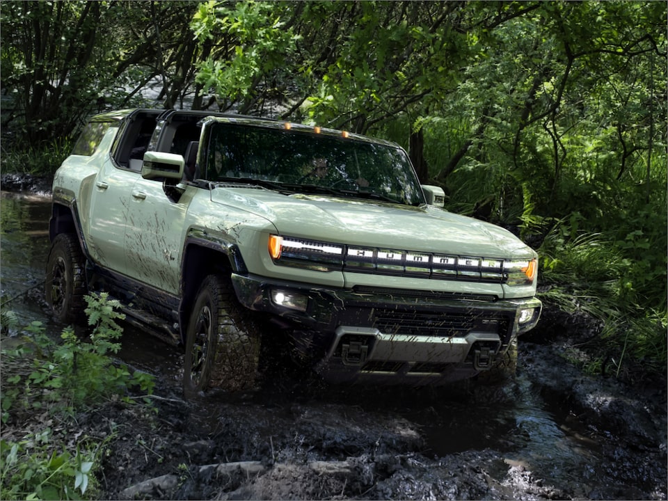 The Hummer EV Driving Off-Road on a Rocky Woodland Trail 