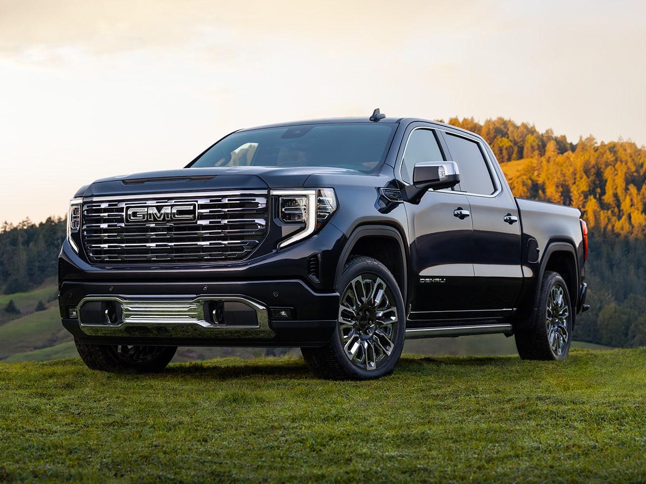 Front Three-Quarters View of the GMC Sierra 1500 Parked in a Green Valley with Rolling Hills in the Distance
