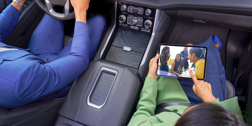 A Birds-Eye View of the Interior of a Car of a Man Driving and a Woman Sitting in the Passenger Seat Using an iPad