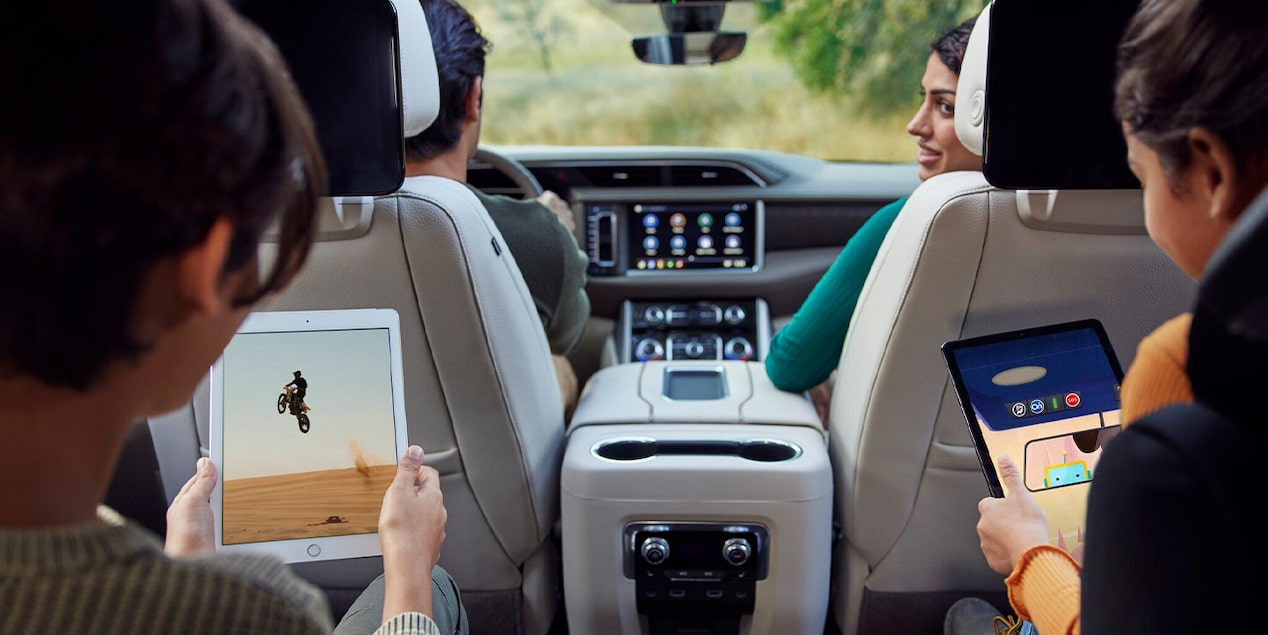 A Family of Four Driving Down the Road While the Kids Play on Their iPads in the Rear Seats