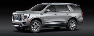 A Sterling Metallic GMC Yukon Denali SUV Is Parked From a Front Three-Quarters Angle Against a Dark Background