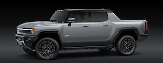 A Gray GMC HUMMER EV Pickup Truck Is Parked From a Front Three-Quarters Angle Against a Dark Background