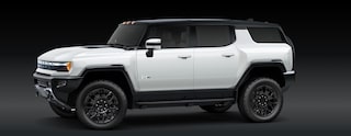 A White GMC HUMMER EV SUV Is Parked From a Front Three-Quarters Angle Against a Dark Background