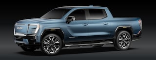 A Blue GMC Sierra EV Denali Electric Pickup Truck Is Parked From a Front Three-Quarters Angle Against a Dark Background