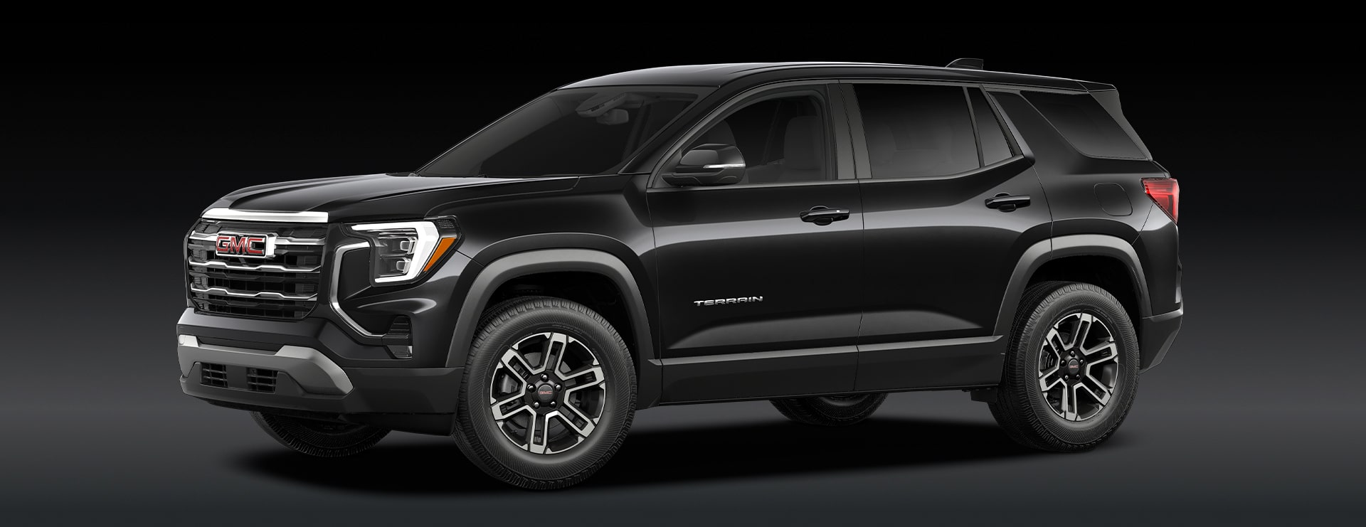 A Black GMC Terrain SUV Is Parked From a Front Three-Quarters Angle Against a Dark Background