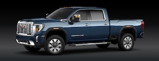 A Downpour Metallic Blue GMC Sierra 2500 Denali HD Pickup Truck Is Parked From a Front Three-Quarters Angle Against a Dark Background