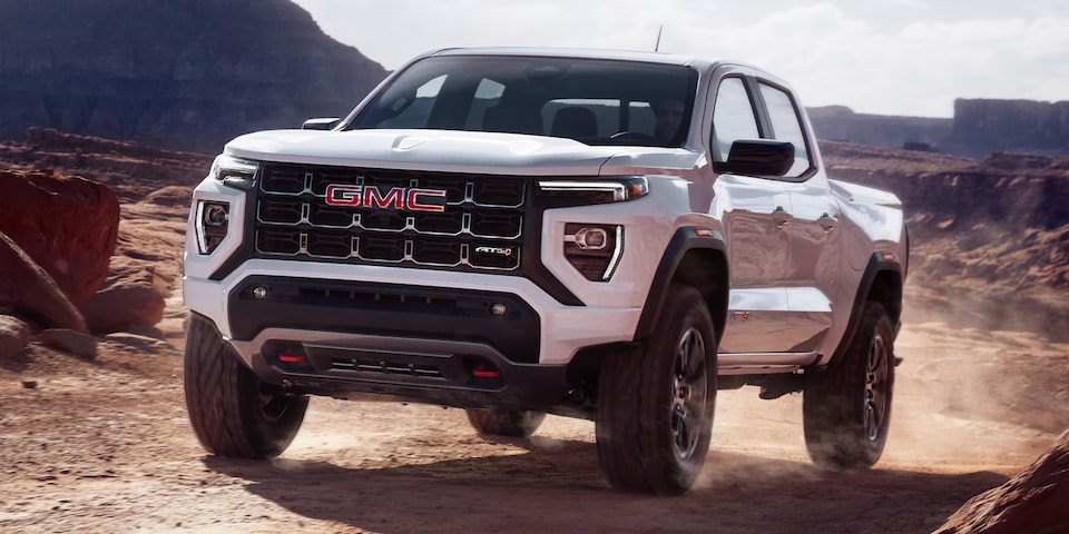 A Summit White 2024 GMC Canyon Driving Off-Road
