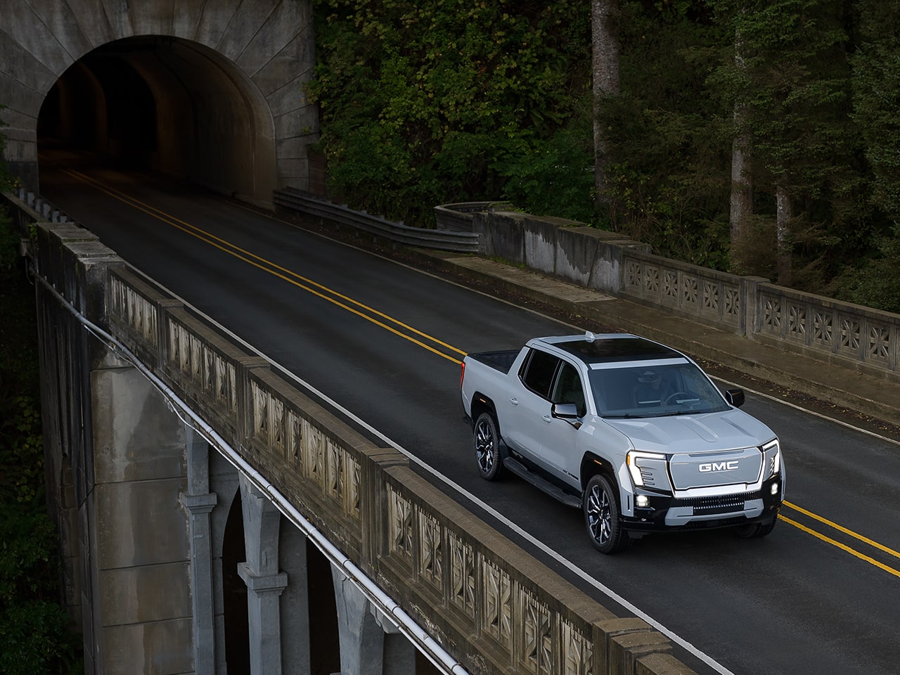 Birds-eye View of the GMC Sierra EV Pickup Truck Driving Over a Bridge
